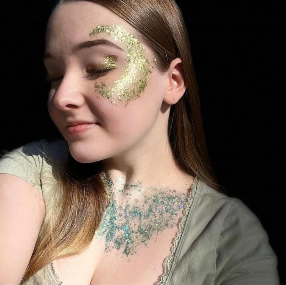 Gold glitter crescent moon face paint with teal glitter neckline for a festival look