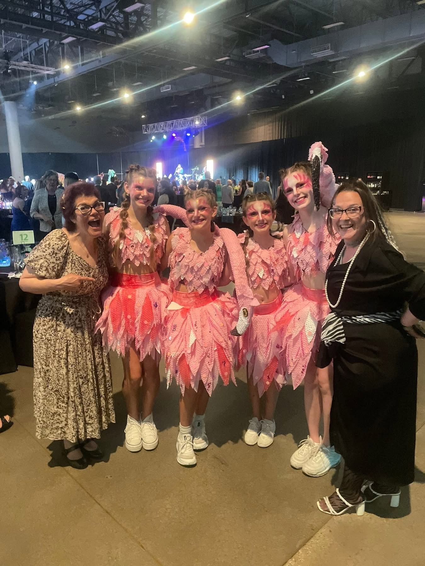 Face painter Tiah with a troupe of pink flamingo performers in matching face paint and costume